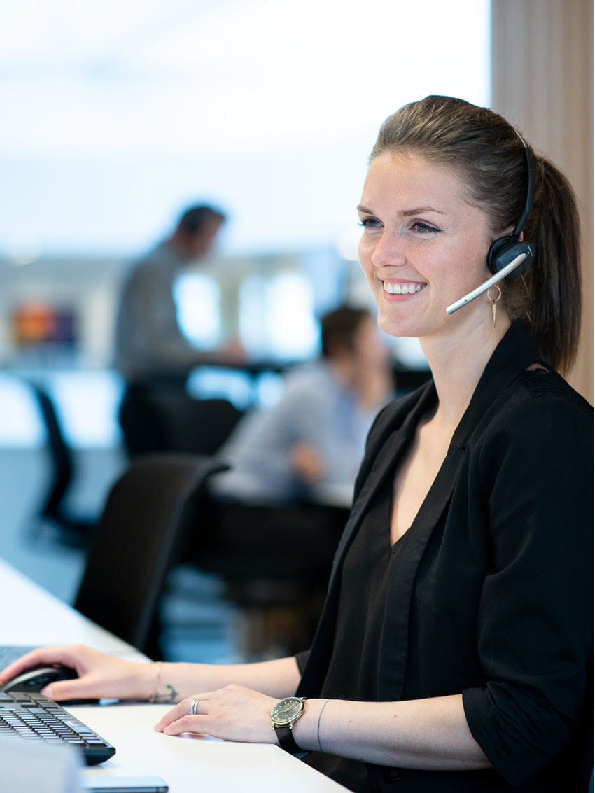 Female employee with headset looking at a computer screen